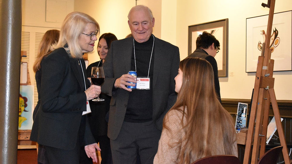 Two alumni tallking to a current students at an event